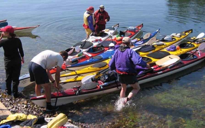 a group of people work to pack kayaks for a day of paddling on an outward bound course for adults 